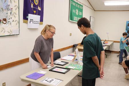 A 4-H member presenting his art project at the 4-H general show.