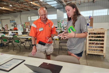 A 4-H member speaks with a volunteer judge about her 4-H project