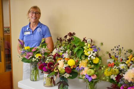 Amy Moore-McKee posing with flower arrangements.