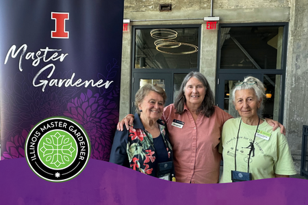 From left, Illinois Extension Master Gardener volunteers Anita Johnson, County Extension Director Margaret Larson, and Master Gardener volunteer Barbara Flores pose together at the 2026 Illinois Master Gardener Conference in Rockford. A purple Illinois Master Gardener banner and logo appear beside them.