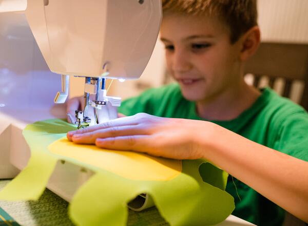 young boy using sewing machine