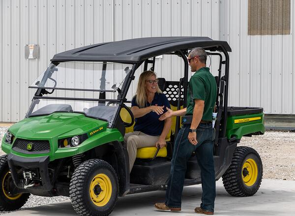 woman in golf cart shaking hands with man