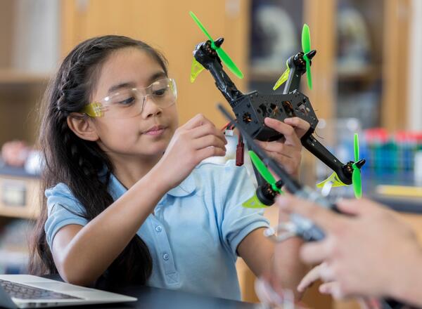 Youth setting up a drone in a lab setting. 