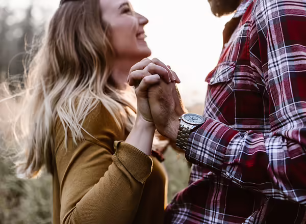 couple holding hands while standing in farm field