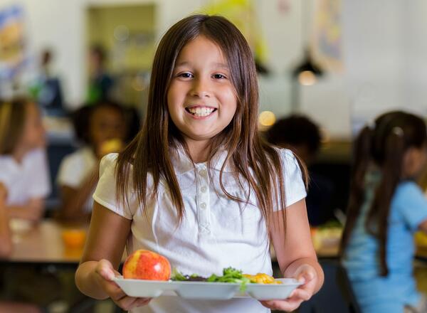 young girl holding plate in lunchroom