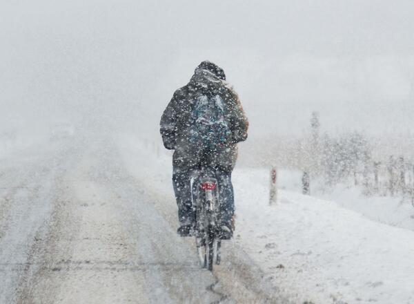 person riding motorcycle on snow coated road