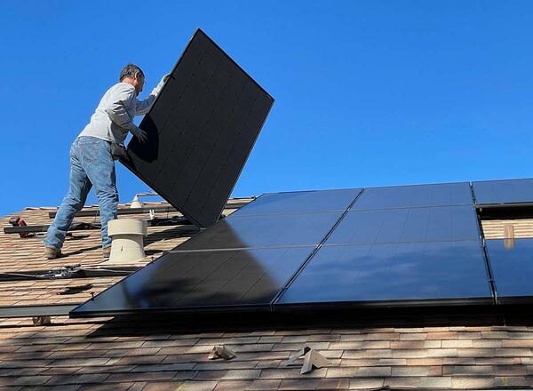 man mounting solar panels on roof