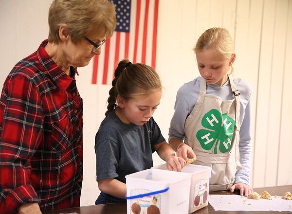 4-H Youth and volunteer measure candy portions.