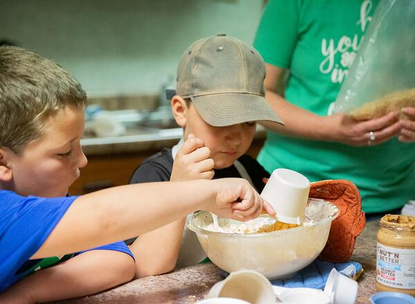 Two 4-Hers work together to measure and mix candy ingredients. 