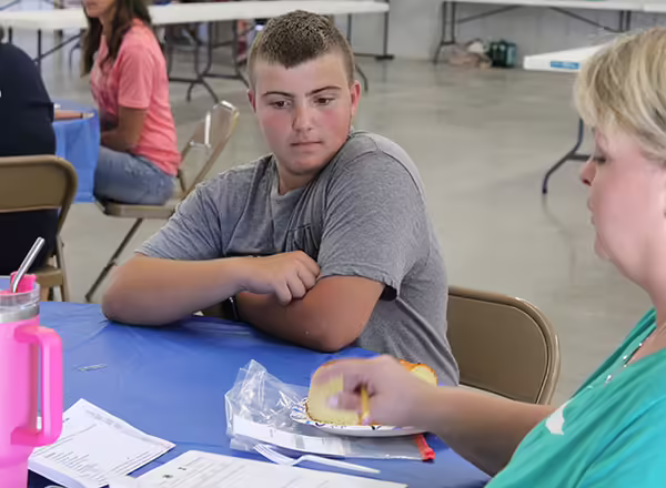 4-H youth discusses his food and clothing show project with judge.