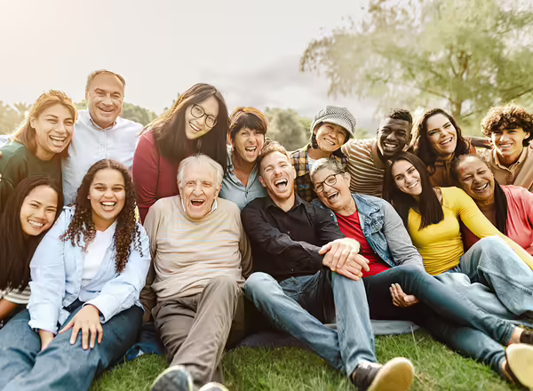 Happy multigenerational people having fun sitting on grass in a public park