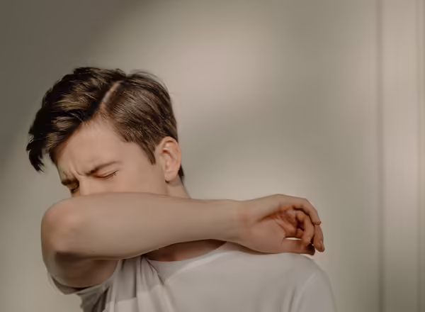 man coughing into arm