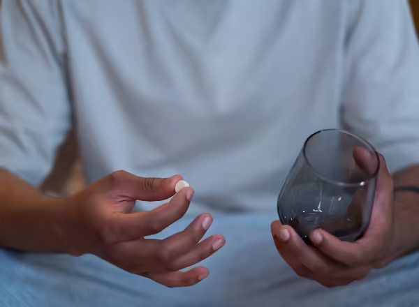 person holding pill and glass of water