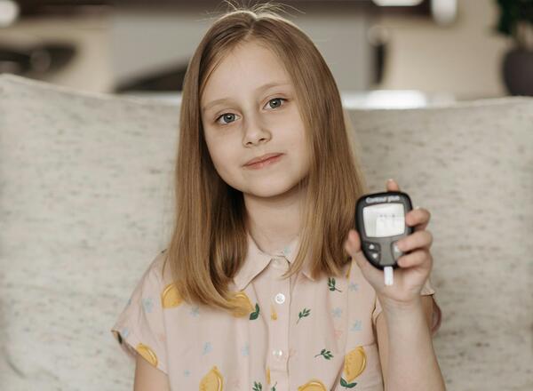 young girl holding diabetes monitor