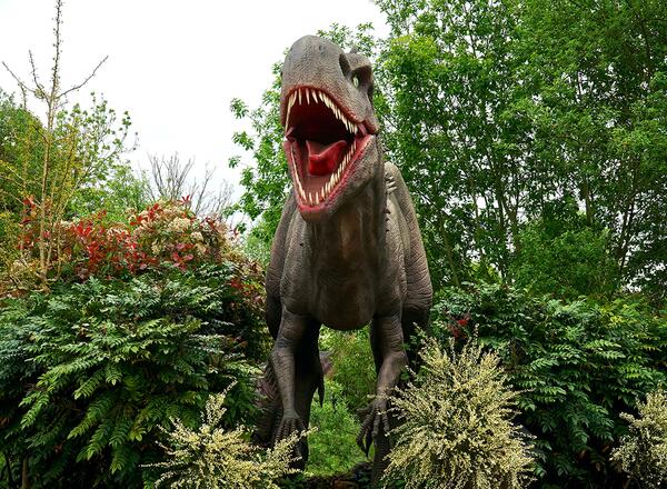 dinosaur statue in field with plants