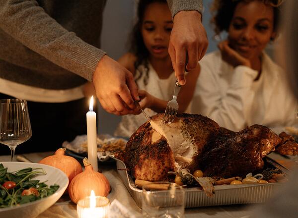 person carving turkey with family watching
