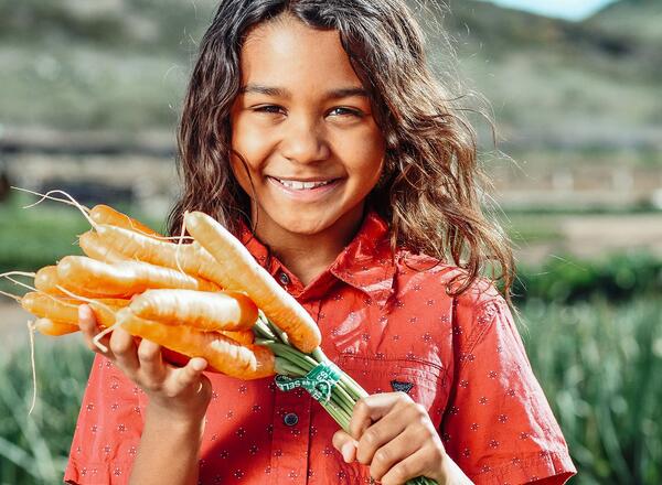 girl holding carrots from the garden