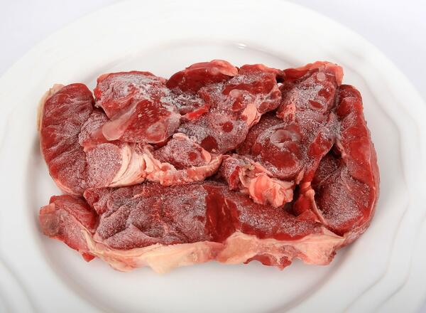 Frozen beef steaks on white plate