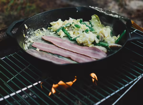 Skillet on grill cooking bacon and eggs