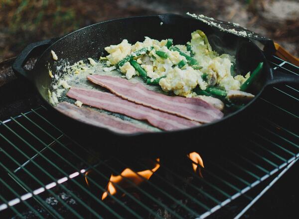 Skillet on grill cooking bacon and eggs