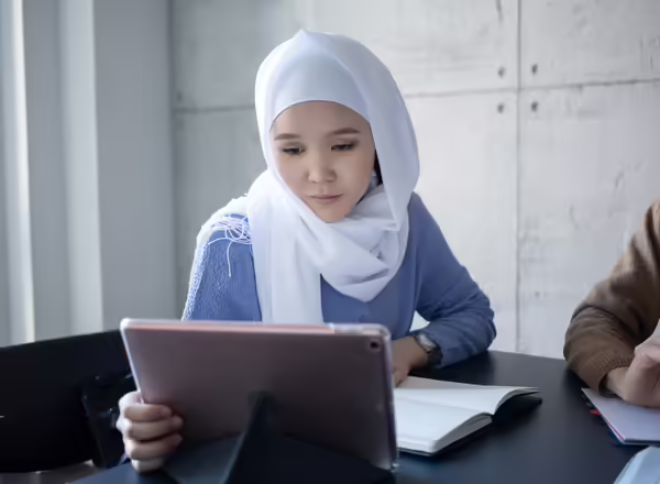 Woman looking at computer and workbook