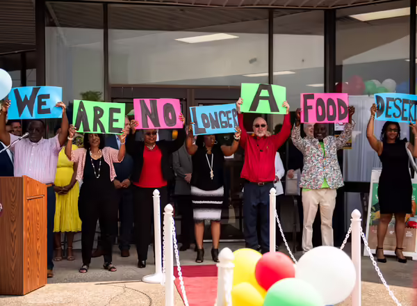 People holding up signs "we are no longer a food desert"