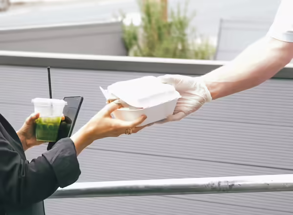 Worker handing to-go food box to customer