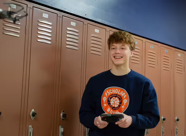 Student pilots a drone in school hallway.