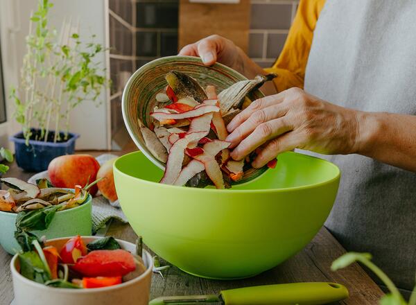 The focus of the picture is a woman's hands sorting her compostable foods into separate bowls.