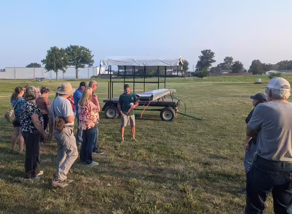 group of people in a field beside a wagon