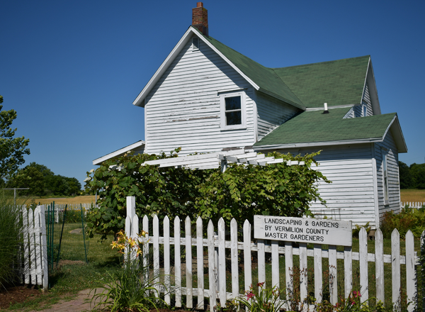 A white house with a picket fence and sign.