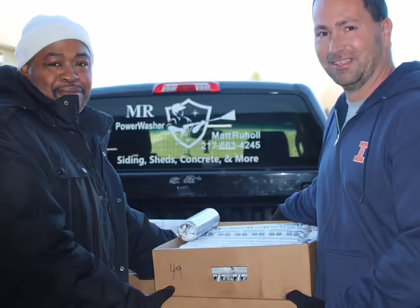 Two adults holding a box of frozen venison for donation.