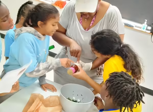 group of four children looking at a nutrition label on a bottle as their teacher points at it