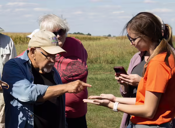 A man examines something someone else is holding on a farm