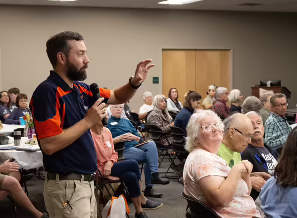 A man with a microphone speaks to the room