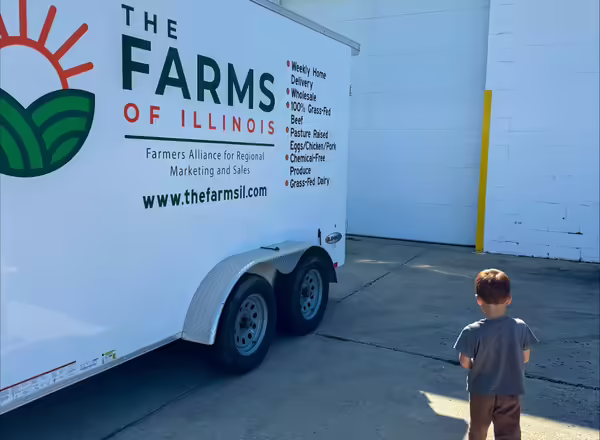 Clint's son stands next to a Farms of Illinois trailer