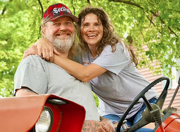 Scott and Anna Hoffman hug while sitting on a tractor