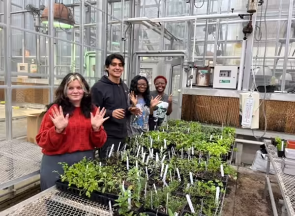 young students in a greenhouse learning about plants