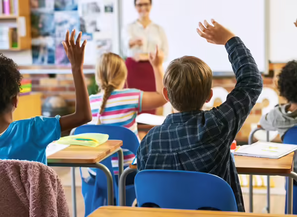 Kids raising their hands in classroom