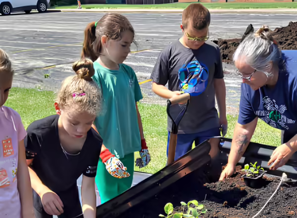 children learning about gardening in a raised garden bed.