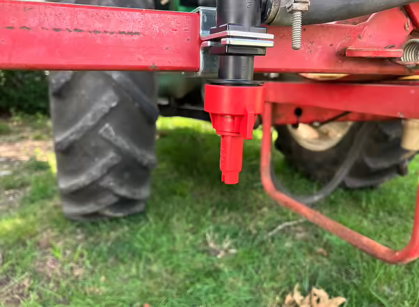 red plastic nozzle attached to a fitting on the back of a tractor
