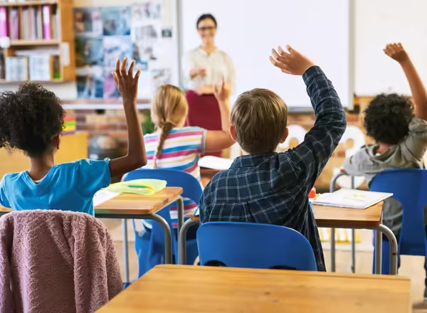 students in a classroom raising their hands