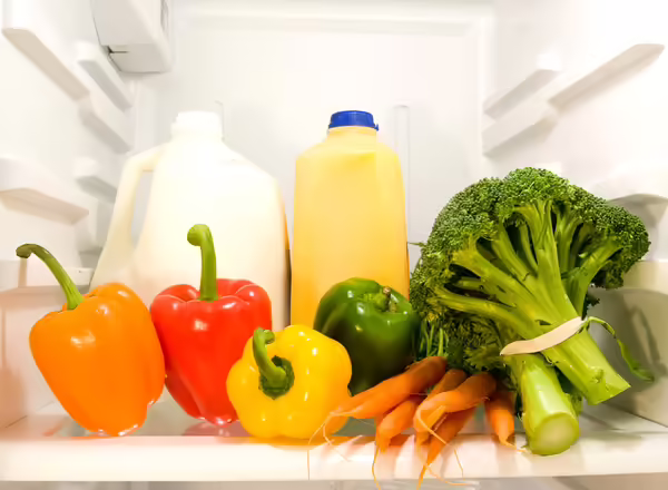 milk, juice, and raw vegetables on refrigerator shelf
