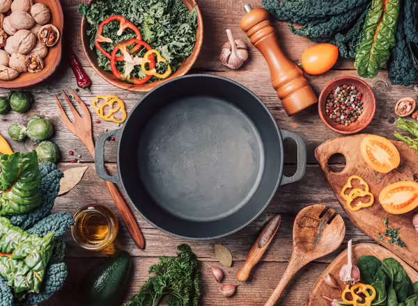 Various produce ingredients around an empty pot.