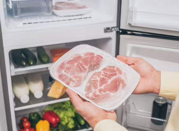 A person taking frozen meat out of the freezer