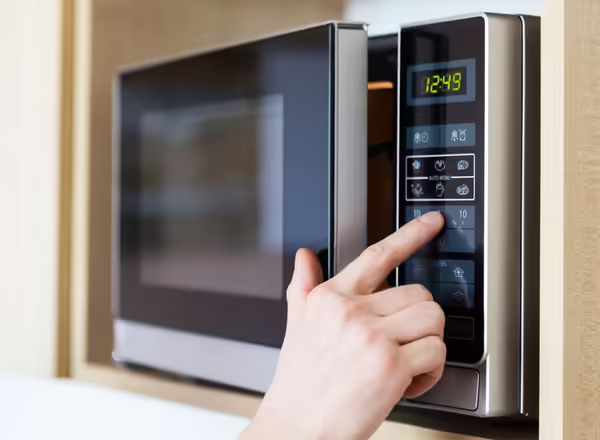 A person pressing buttons on a microwave
