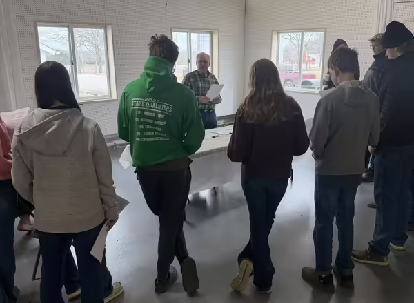 Group of youth stand around a presenter who is speaking to them