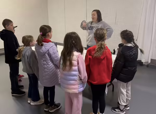 Group of youth stand around a presenter who is speaking to them