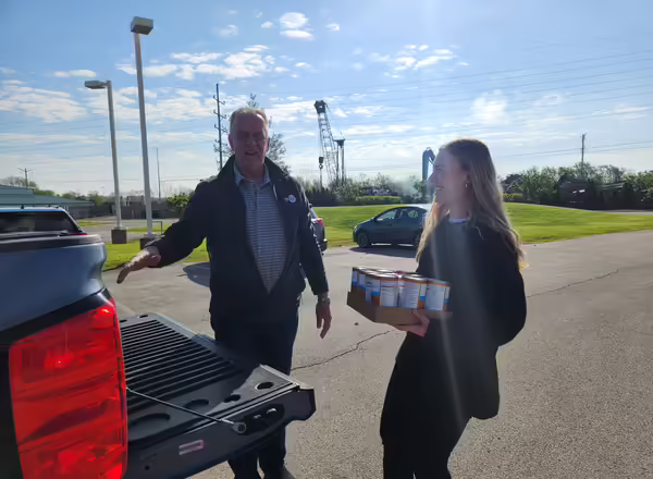 Two people unload food donations from the back of a pickup truck