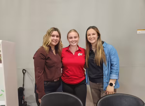Three people, one wearing a red farm bureau polo, pose for a picture